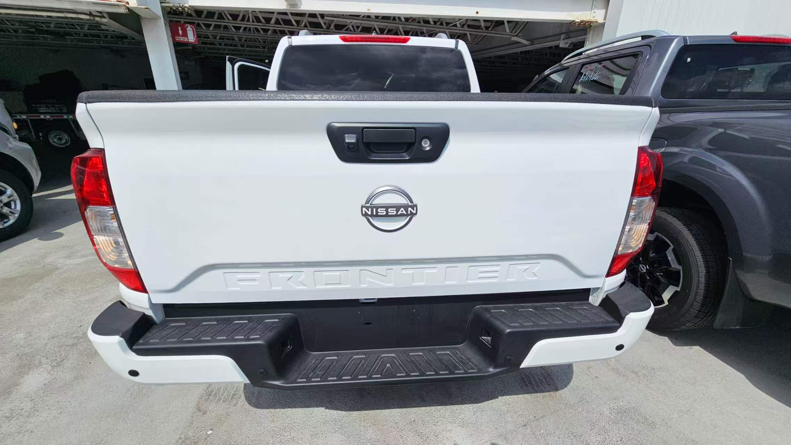 Rear of a white Nissan pickup showing the tailgate handle and bumper