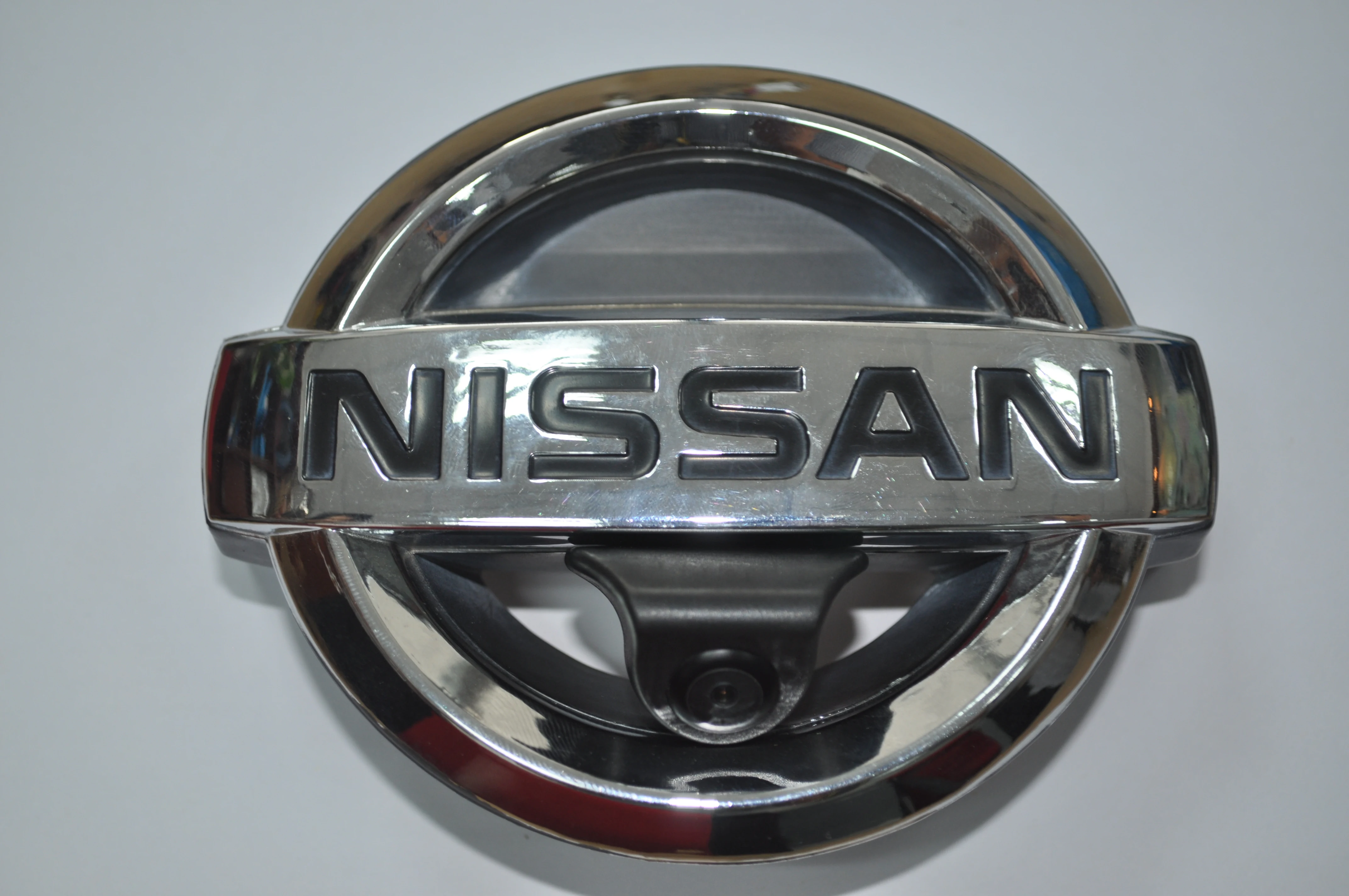 Close-up of the CAM-FN01 camera integrated into a Nissan front emblem