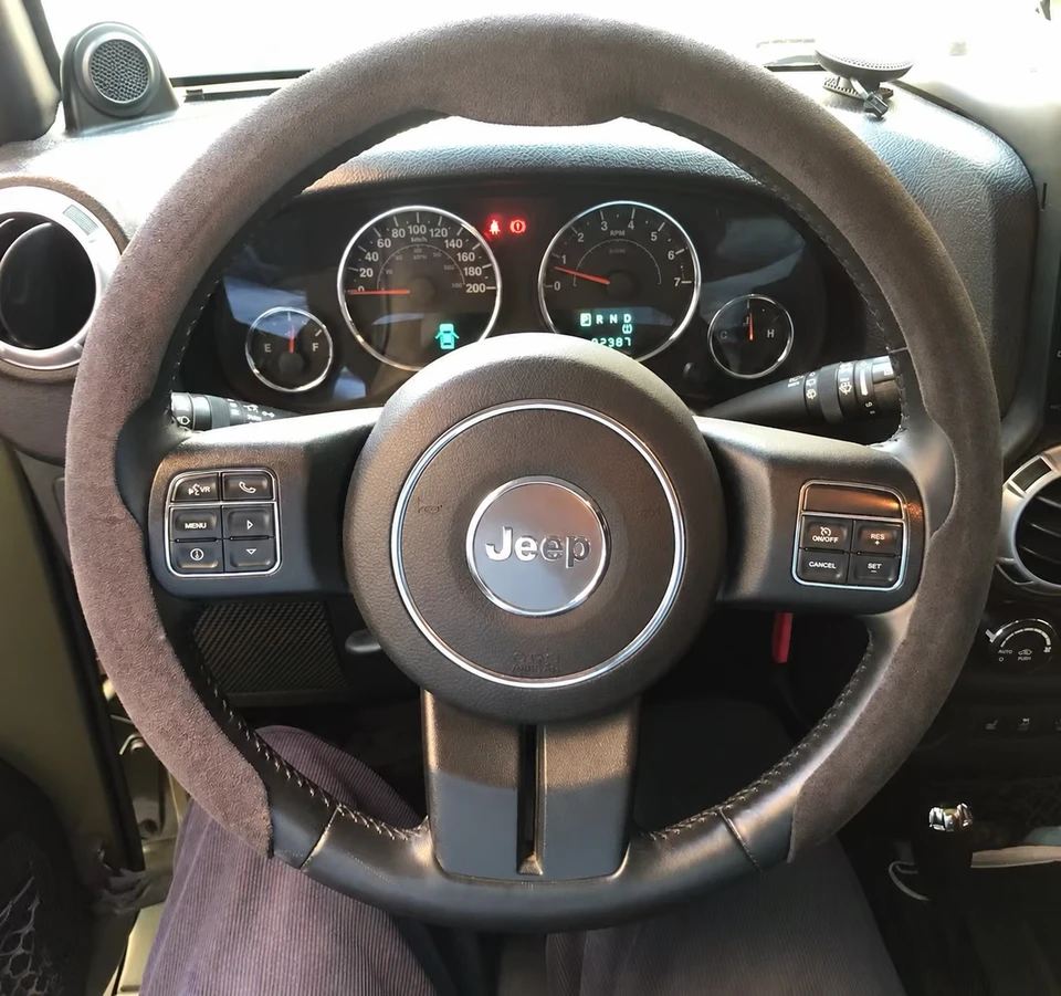 Heated steering wheel cover on a Jeep wheel; promotional overlay removed and obscured area reconstructed